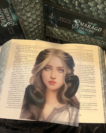 Das Page Overlay zeigt das Porträt der weiblichen Hauptfigur des Buches "Der Smaragddrache". Gemma hat langes, hellblondes Haar. Sie trägt ein helles Oberteil. Auf ihre Schultern und Nacken schlängelt sich ein kleiner Drache.